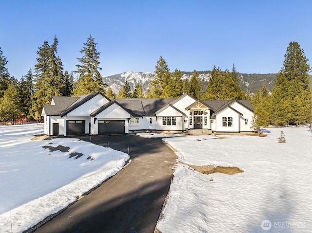 modern inspired farmhouse featuring aphalt driveway, a mountain view, and a garage