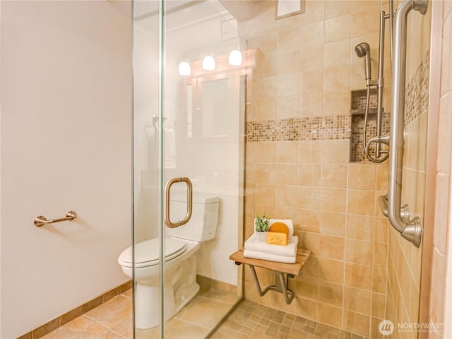 bathroom with toilet, tile patterned flooring, baseboards, and a shower with shower door