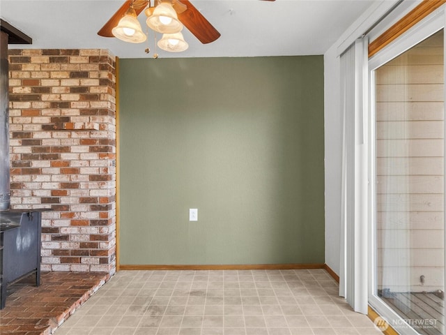 unfurnished living room featuring a wood stove, ceiling fan, and baseboards