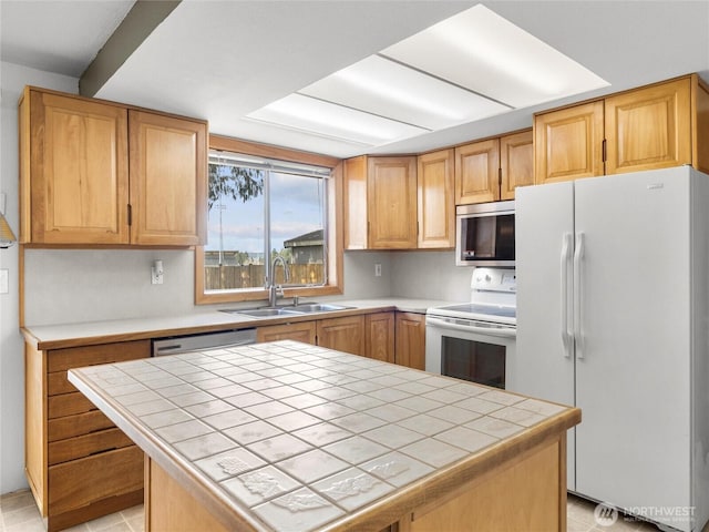 kitchen featuring tile countertops, white appliances, a sink, and a center island