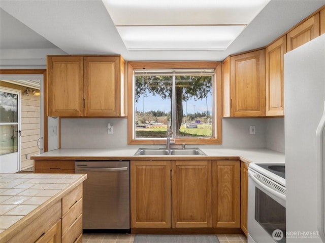 kitchen with tile countertops, white appliances, and a sink