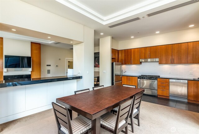 kitchen with brown cabinetry, visible vents, stainless steel appliances, and decorative backsplash