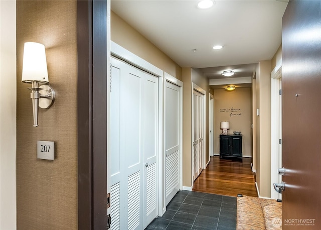 hallway with dark tile patterned floors, recessed lighting, and baseboards