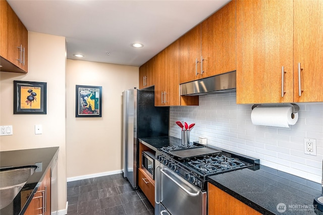 kitchen with decorative backsplash, appliances with stainless steel finishes, under cabinet range hood, dark countertops, and brown cabinets