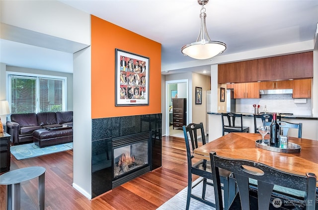 dining area featuring dark wood-type flooring, baseboards, and a tile fireplace