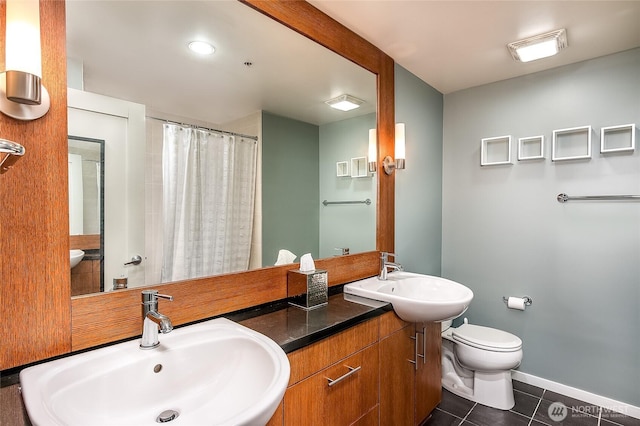 bathroom featuring tile patterned floors, toilet, baseboards, and a sink