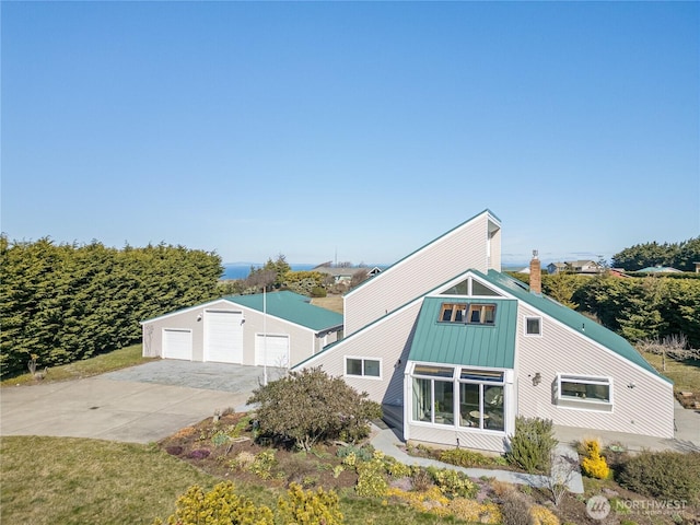 view of front facade featuring an outbuilding, metal roof, a garage, a standing seam roof, and a chimney