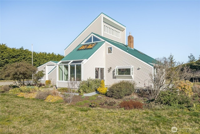 view of property exterior with metal roof, a lawn, a chimney, and a sunroom