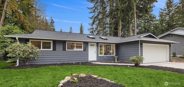 single story home with a front lawn, concrete driveway, and a garage