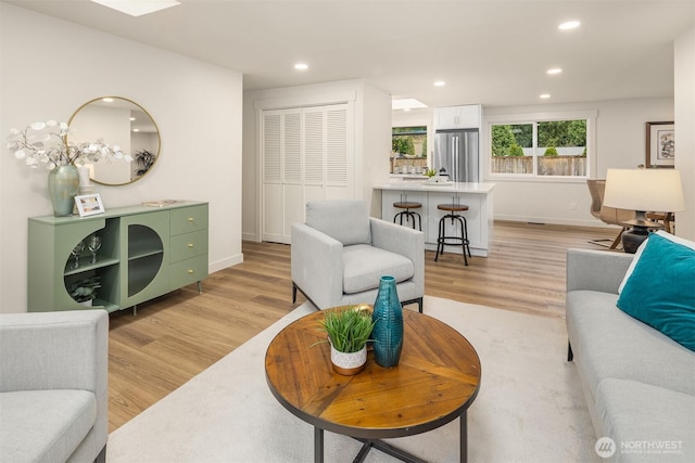 living area with recessed lighting, light wood-type flooring, and baseboards