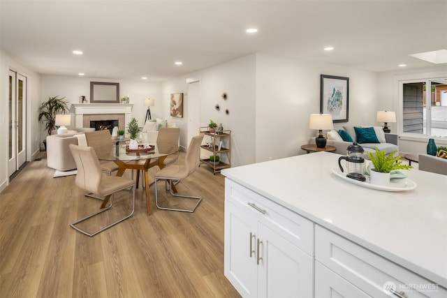 dining space with a glass covered fireplace, light wood-style flooring, and recessed lighting