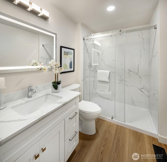 bathroom featuring toilet, wood finished floors, visible vents, and a marble finish shower