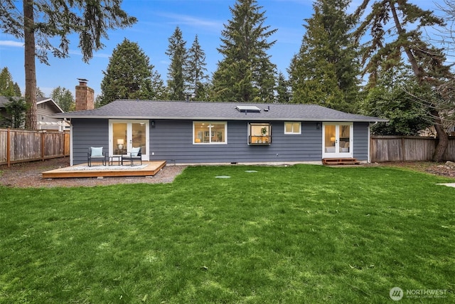 rear view of property featuring a wooden deck, a lawn, a fenced backyard, and french doors