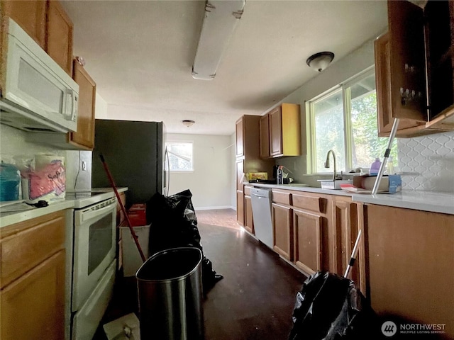 kitchen featuring white appliances, decorative backsplash, a sink, and light countertops