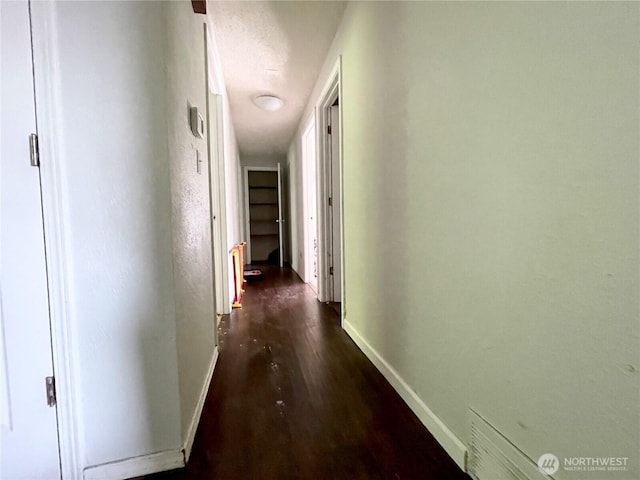 hall featuring dark wood-style floors and baseboards