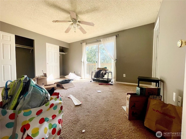 bedroom featuring a ceiling fan, access to outside, a textured ceiling, carpet floors, and two closets