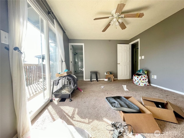 interior space featuring a textured ceiling, carpet, a ceiling fan, and baseboards