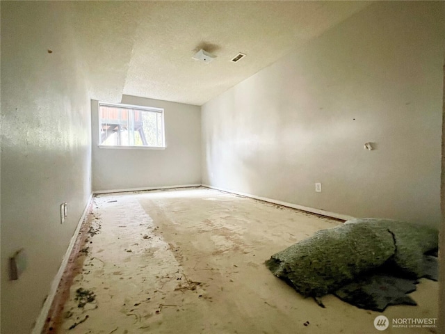 empty room with visible vents, vaulted ceiling, and a textured ceiling