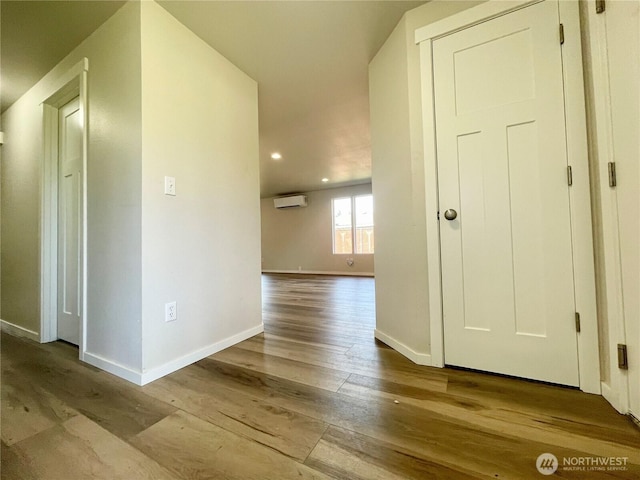 hallway featuring recessed lighting, baseboards, wood finished floors, and a wall mounted air conditioner