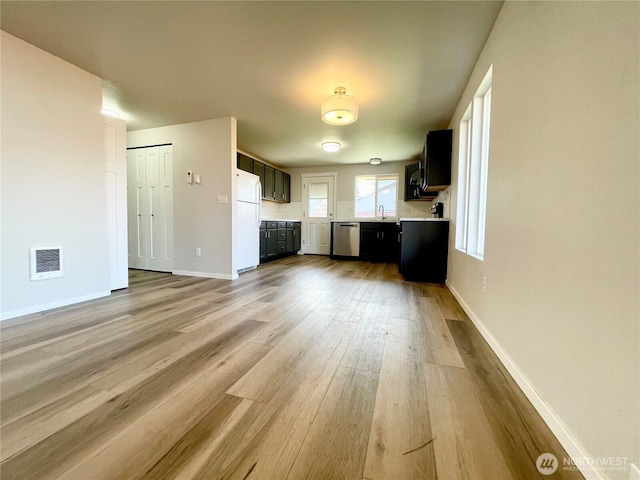 kitchen featuring light countertops, visible vents, stainless steel dishwasher, freestanding refrigerator, and a sink