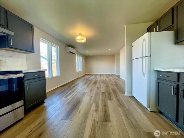 kitchen with electric range, decorative backsplash, light wood-style flooring, freestanding refrigerator, and a wall mounted AC