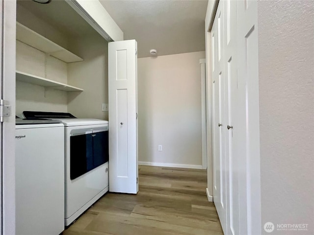 laundry area featuring washer and dryer, laundry area, light wood-style flooring, and baseboards