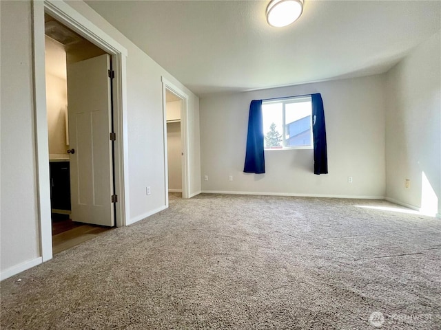 unfurnished bedroom featuring carpet, baseboards, a walk in closet, and a closet