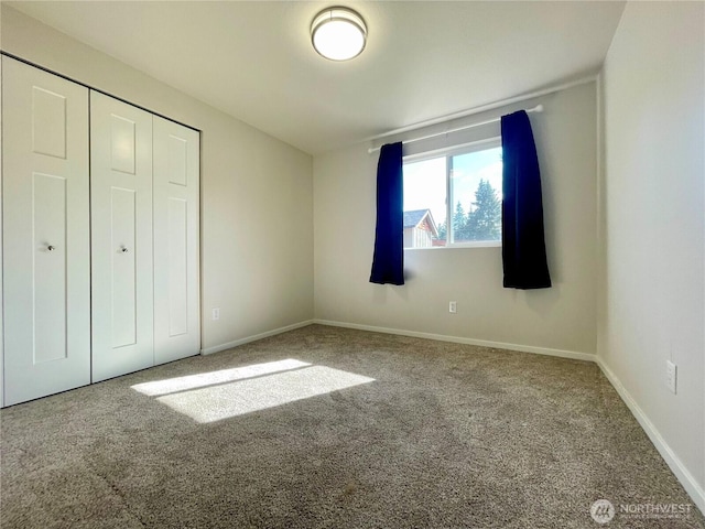 unfurnished bedroom with carpet, a closet, and baseboards