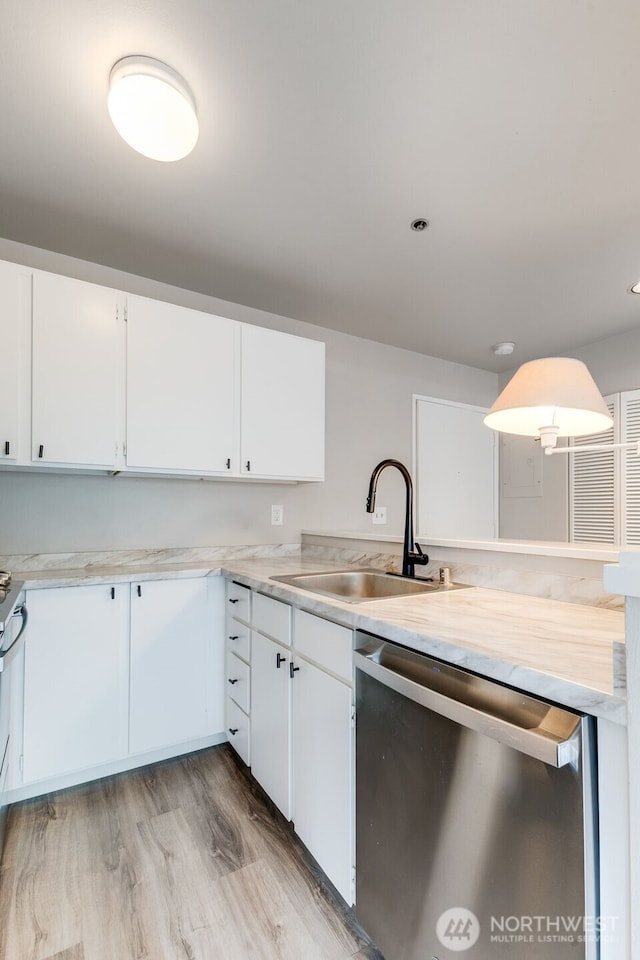 kitchen featuring light countertops, stainless steel dishwasher, a sink, and white cabinetry