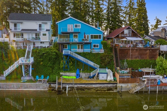 back of house featuring stairway, a water view, and a residential view