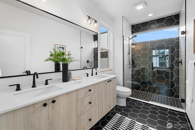 bathroom with a sink, toilet, double vanity, and a shower stall