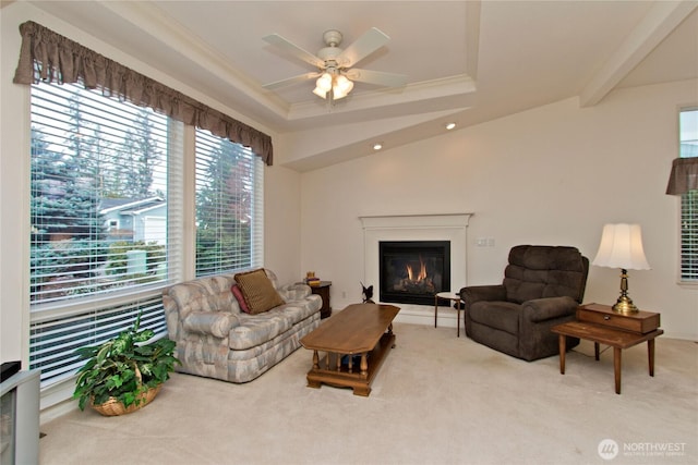 carpeted living area featuring crown molding, recessed lighting, a raised ceiling, a ceiling fan, and a glass covered fireplace