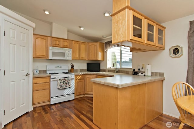 kitchen featuring lofted ceiling, glass insert cabinets, dark wood-type flooring, white appliances, and a peninsula