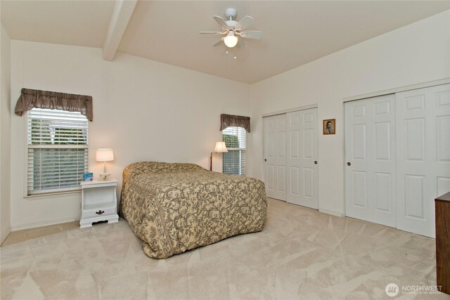 carpeted bedroom with beam ceiling, ceiling fan, and two closets