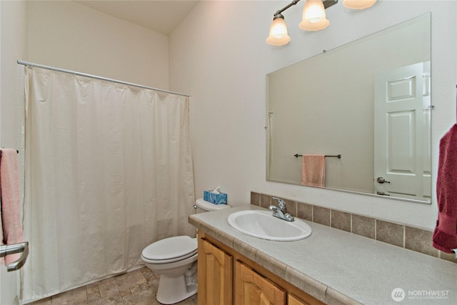 bathroom featuring stone finish floor, vanity, and toilet