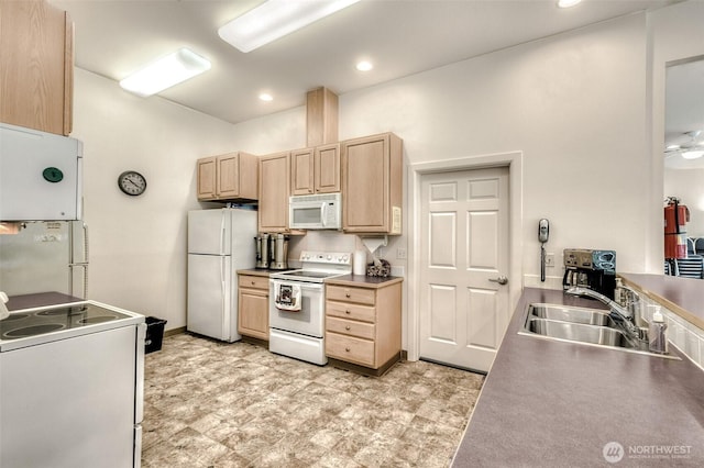 kitchen with white appliances, light brown cabinets, a sink, and recessed lighting