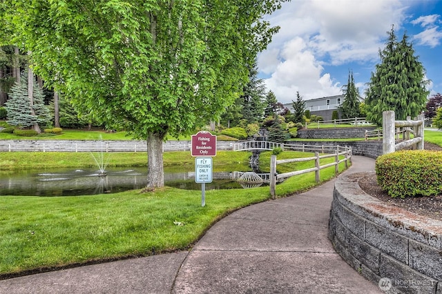 surrounding community featuring a water view and a lawn