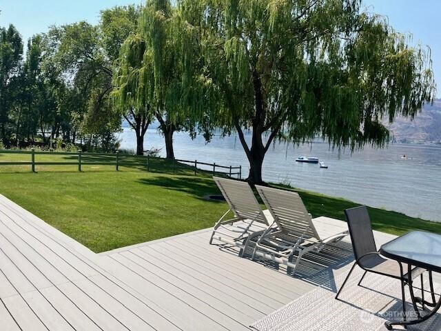 wooden terrace with a water view and a lawn