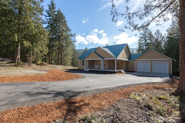 view of front of house with aphalt driveway, covered porch, metal roof, and a garage