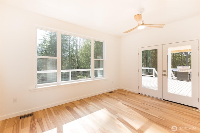 spare room featuring baseboards, french doors, light wood-style floors, and a healthy amount of sunlight