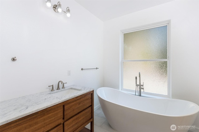 full bathroom with a freestanding bath, vanity, and tile patterned floors