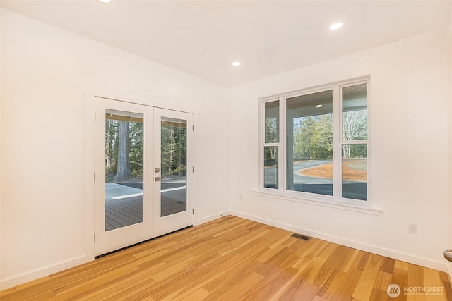 spare room with a healthy amount of sunlight, light wood-type flooring, visible vents, and french doors