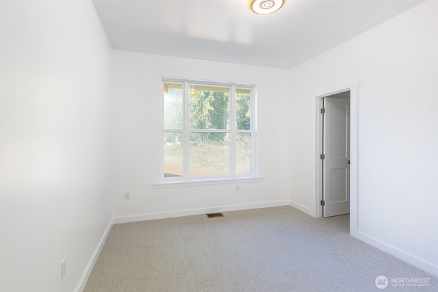 empty room featuring light carpet, visible vents, and baseboards