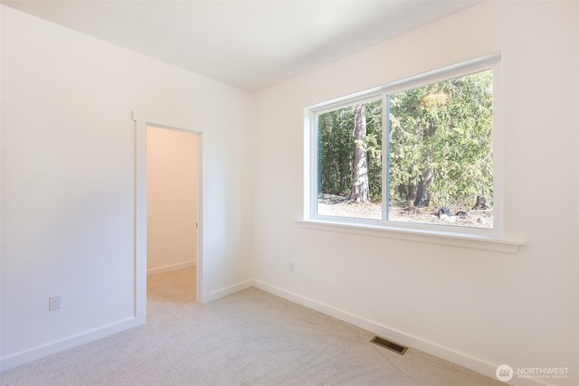 empty room with visible vents, light carpet, and baseboards