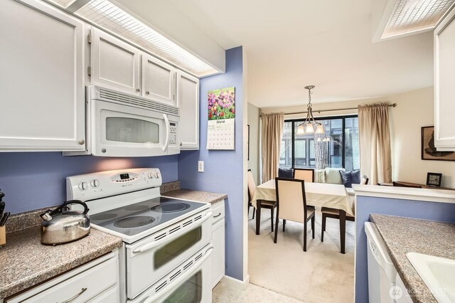 kitchen featuring decorative light fixtures, a chandelier, light countertops, white cabinets, and white appliances