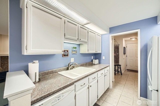 kitchen featuring light tile patterned flooring, white appliances, white cabinetry, and a sink