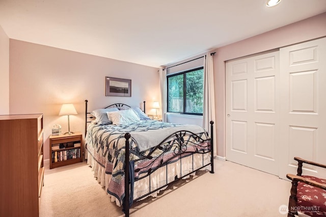 bedroom featuring light carpet, baseboards, and a closet