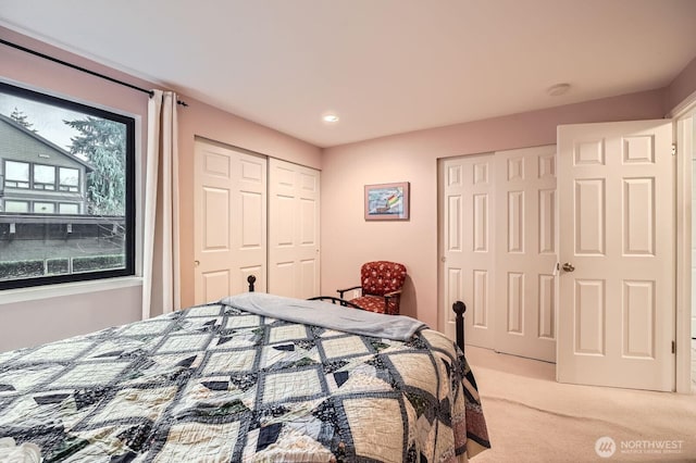 bedroom featuring multiple closets and light colored carpet