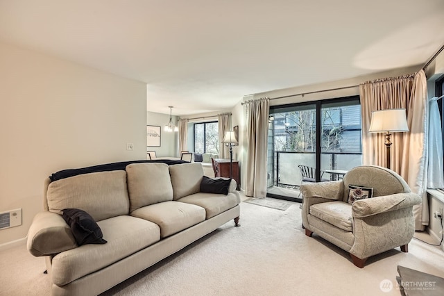 living area featuring visible vents, light carpet, and a notable chandelier