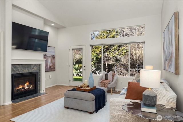 living room with lofted ceiling, recessed lighting, a premium fireplace, wood finished floors, and baseboards